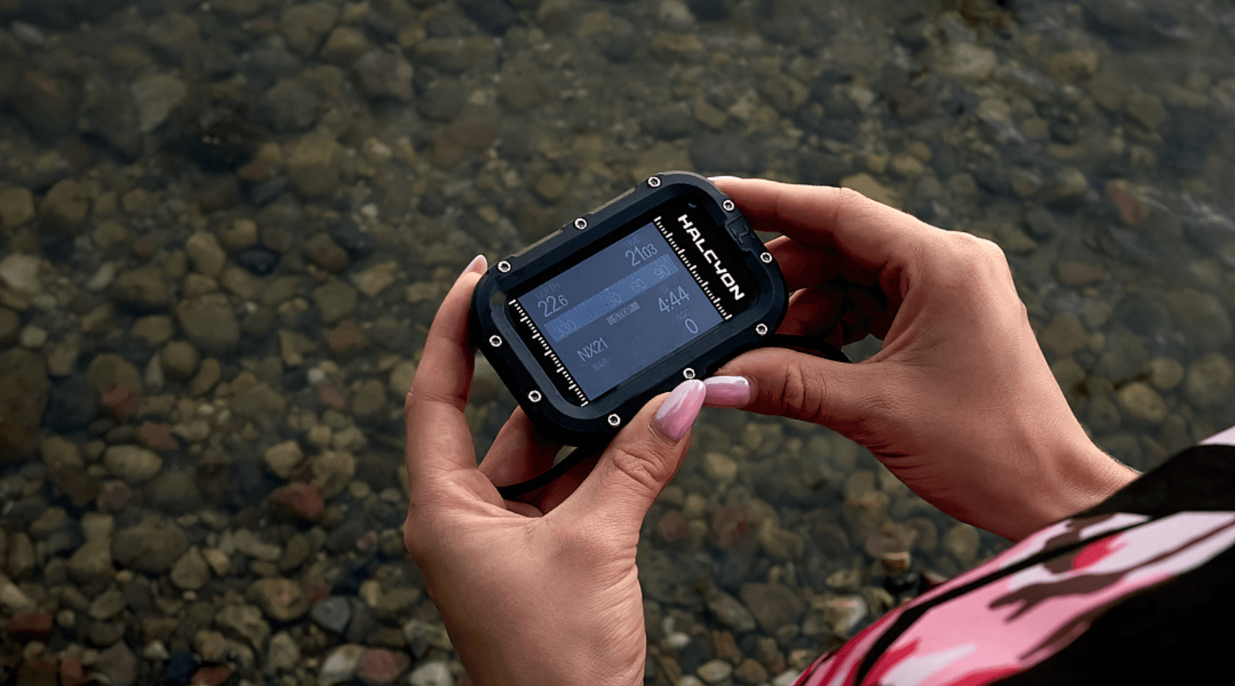 Woman holding Symbios computer in her hand next to a lake